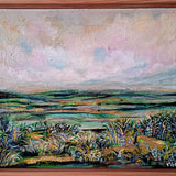 Framed painting of a landscape with a wooden frame on a white wall